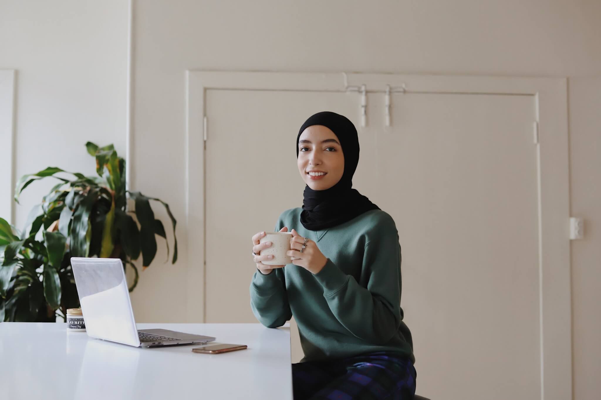 person sitting at a table with their laptop and coffee