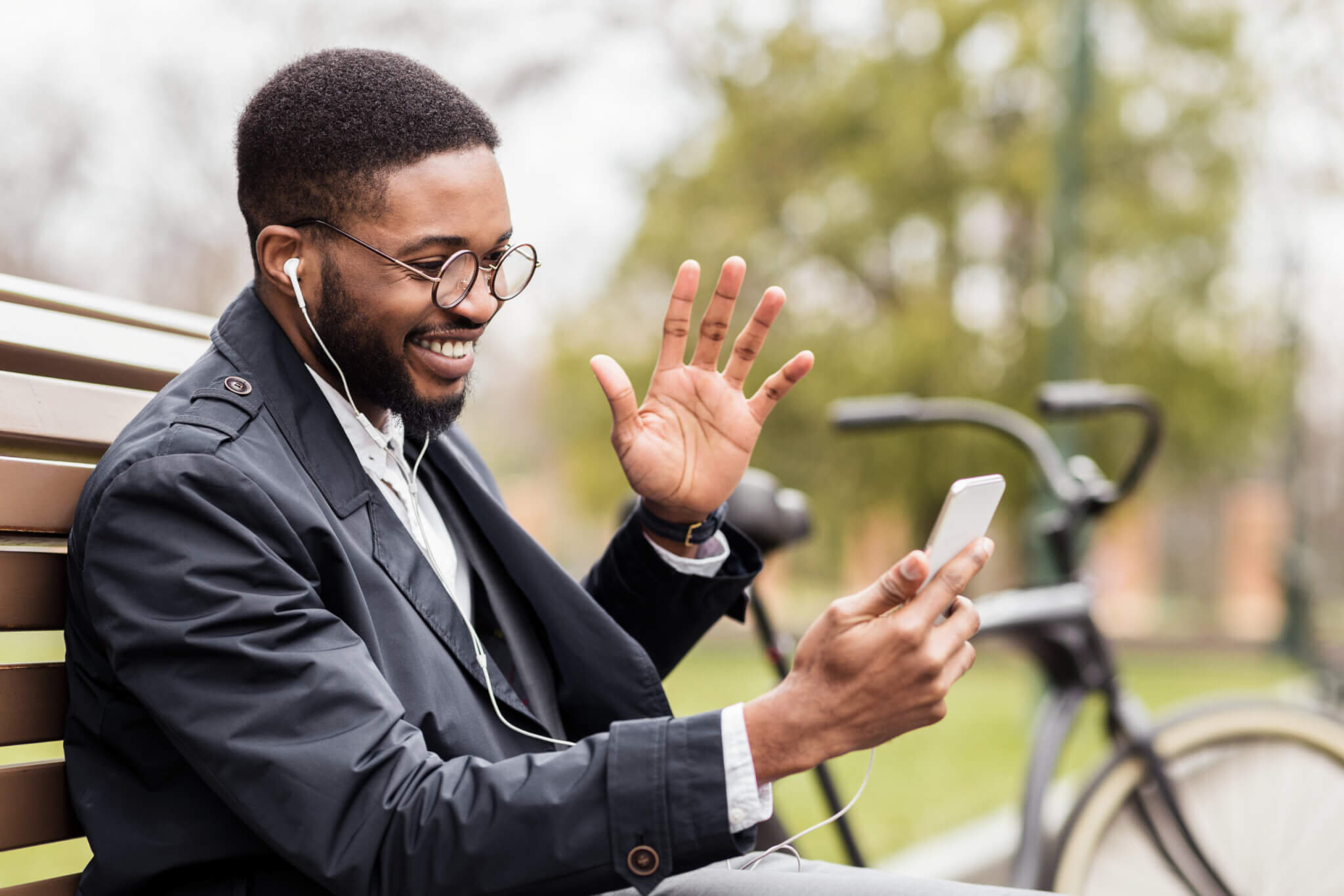 Video call. Happy businessman sitting on bench and using phone, communicating online
