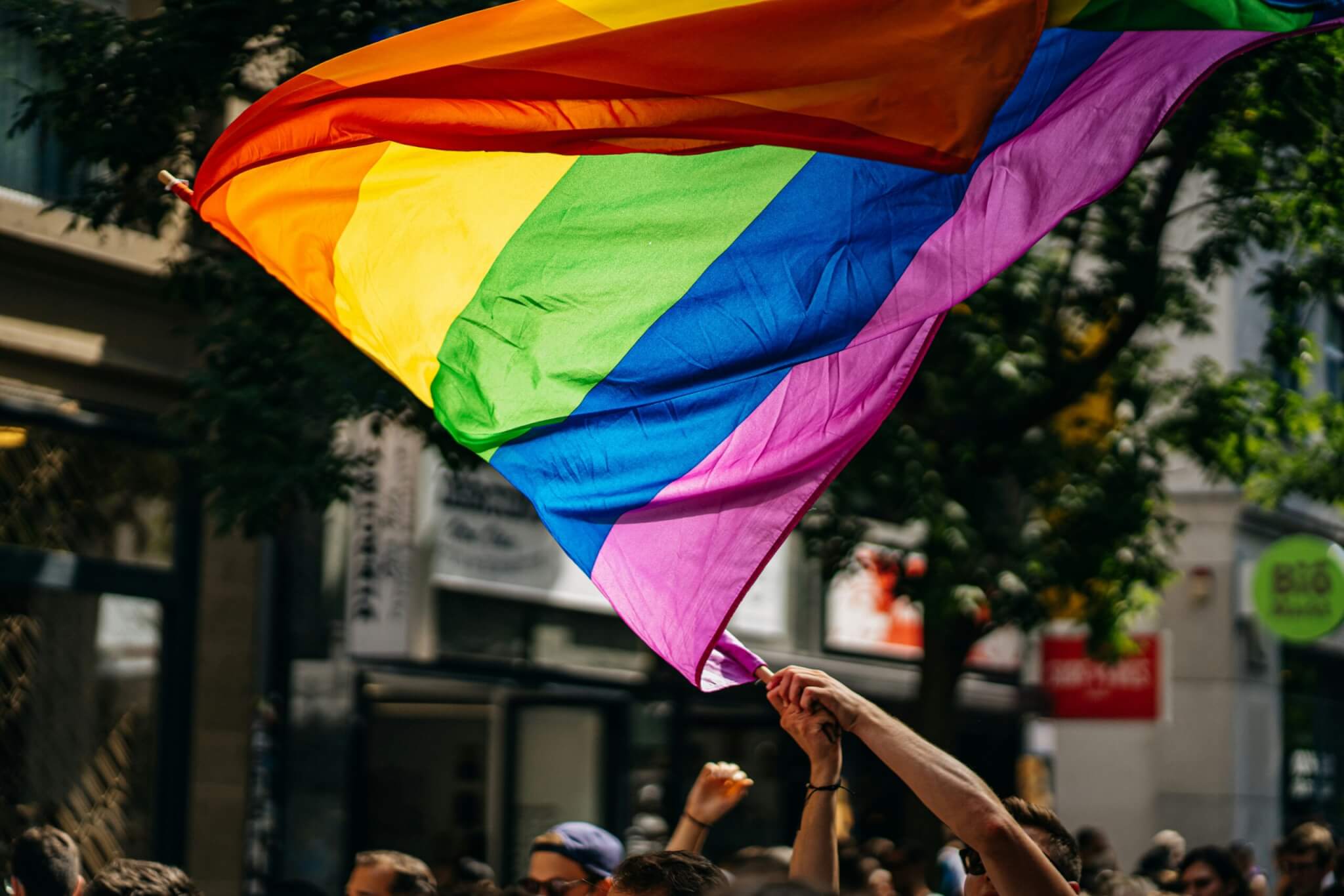 A Pride flag blowing in the wind outside