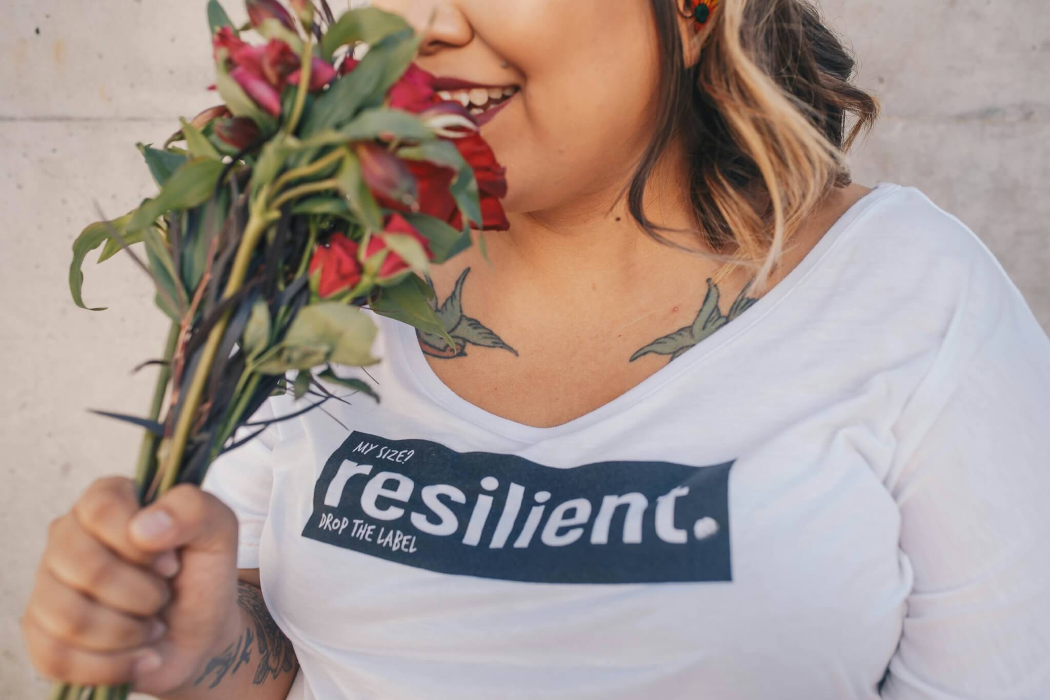 Image of a person holding flowers with the word "resilient" on their shirt