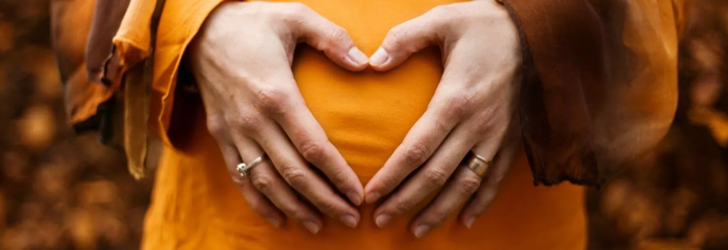 A woman makes a heart shape over her mid drift