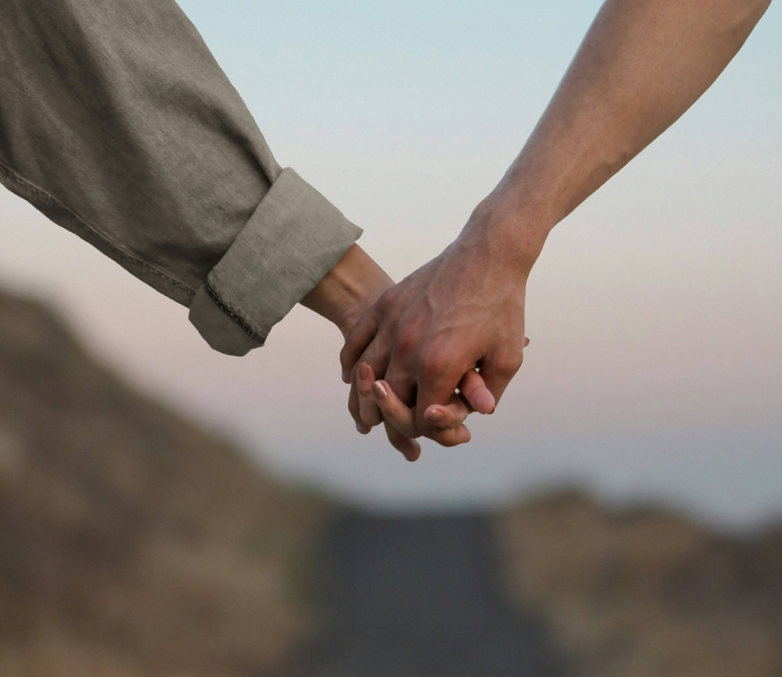 Close-up of two people holding hands, symbolizing support, resilience, and emotional well-being