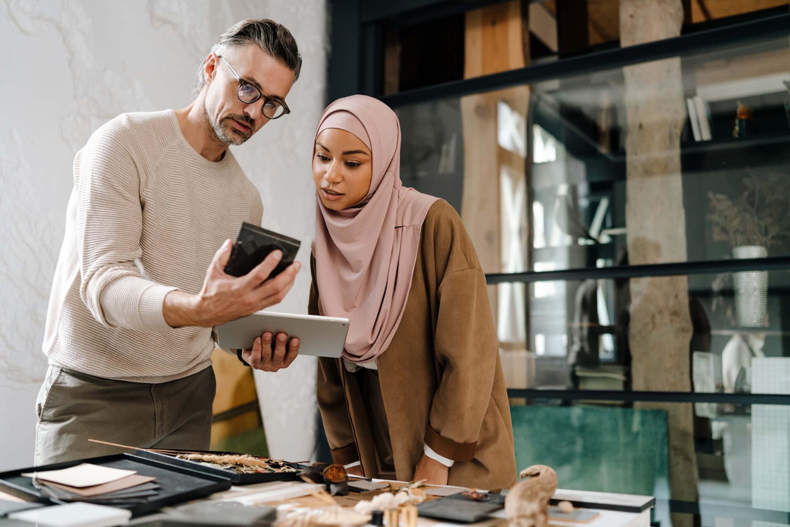 Male and female colleagues reviewing a sample and tablet together in a modern workspace.
