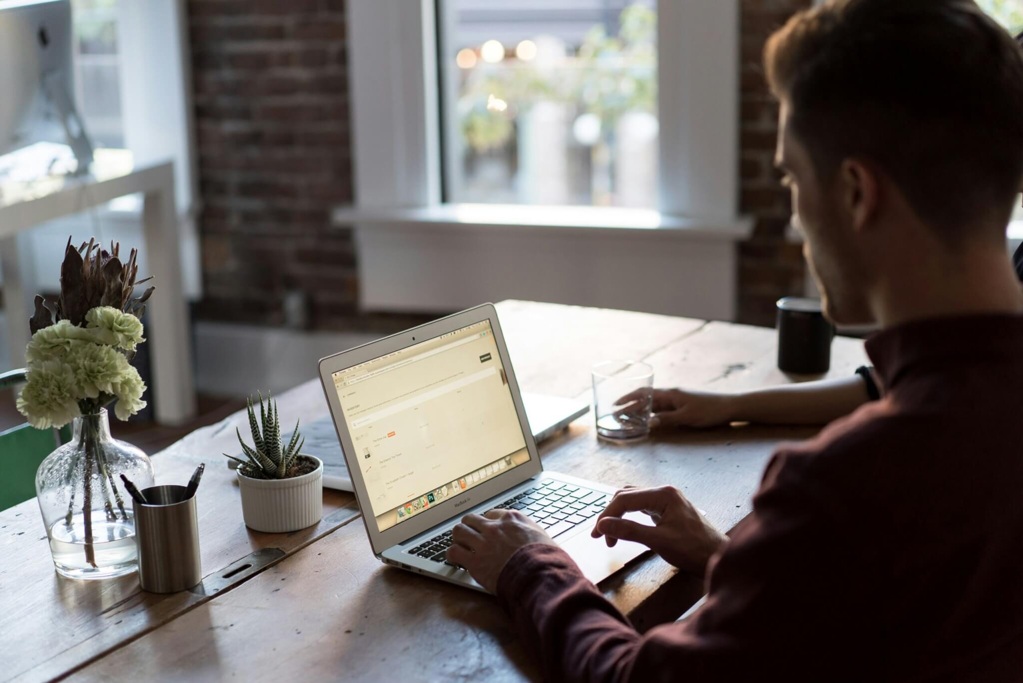 someone sitting at their table using a laptop